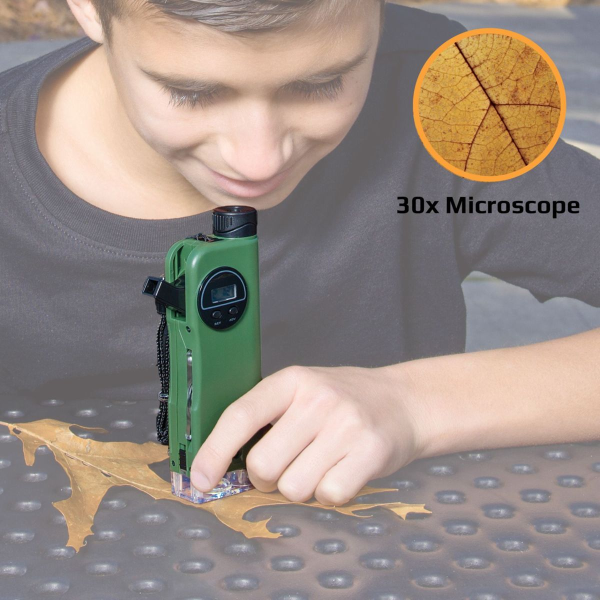 Junge untersucht Blatt mit grünem 30x Mikroskop auf einem Tisch.