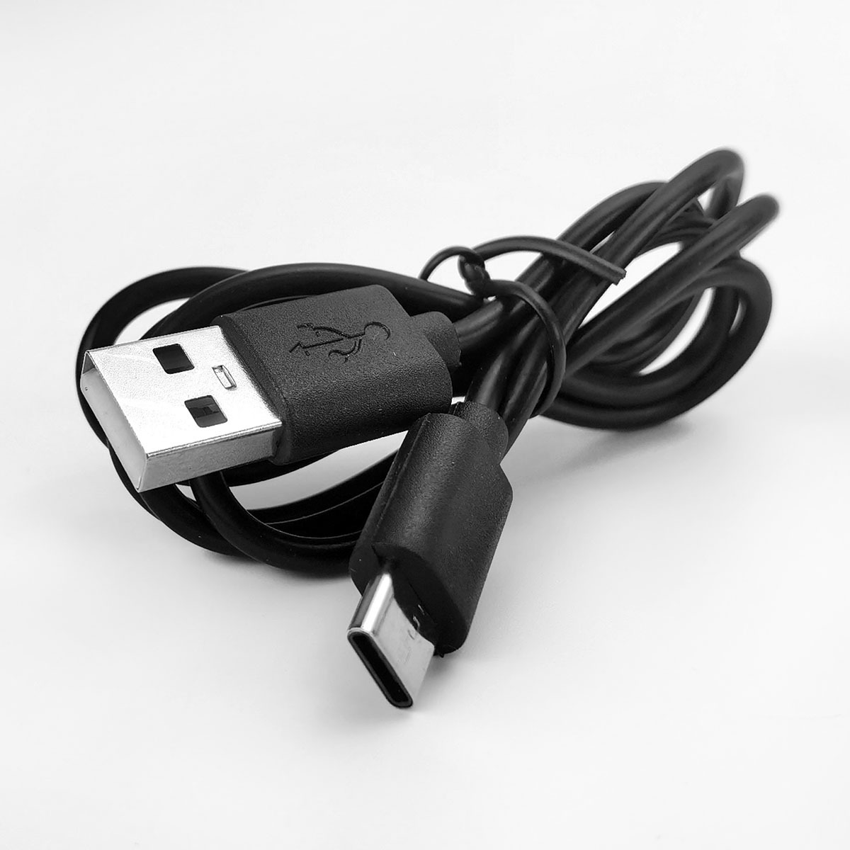 Ein schwarzes USB-A-zu-USB-C-Kabel liegt auf weißem Hintergrund.