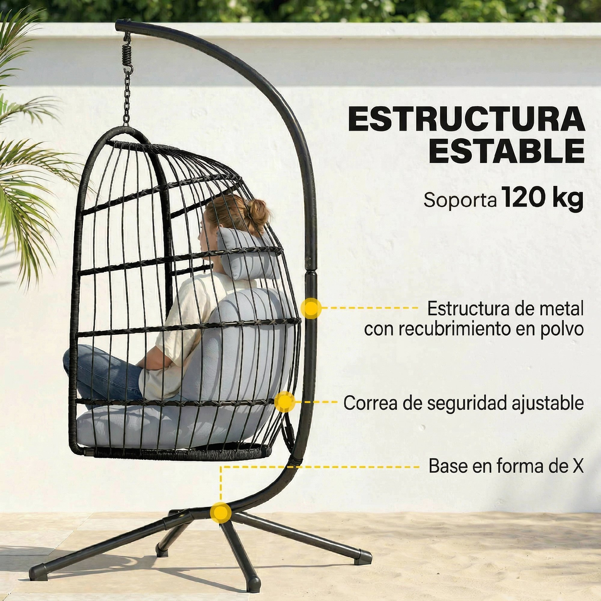 Una mujer sentada en una silla colgante negra con cojines grises. Estructura metálica con base en X.
