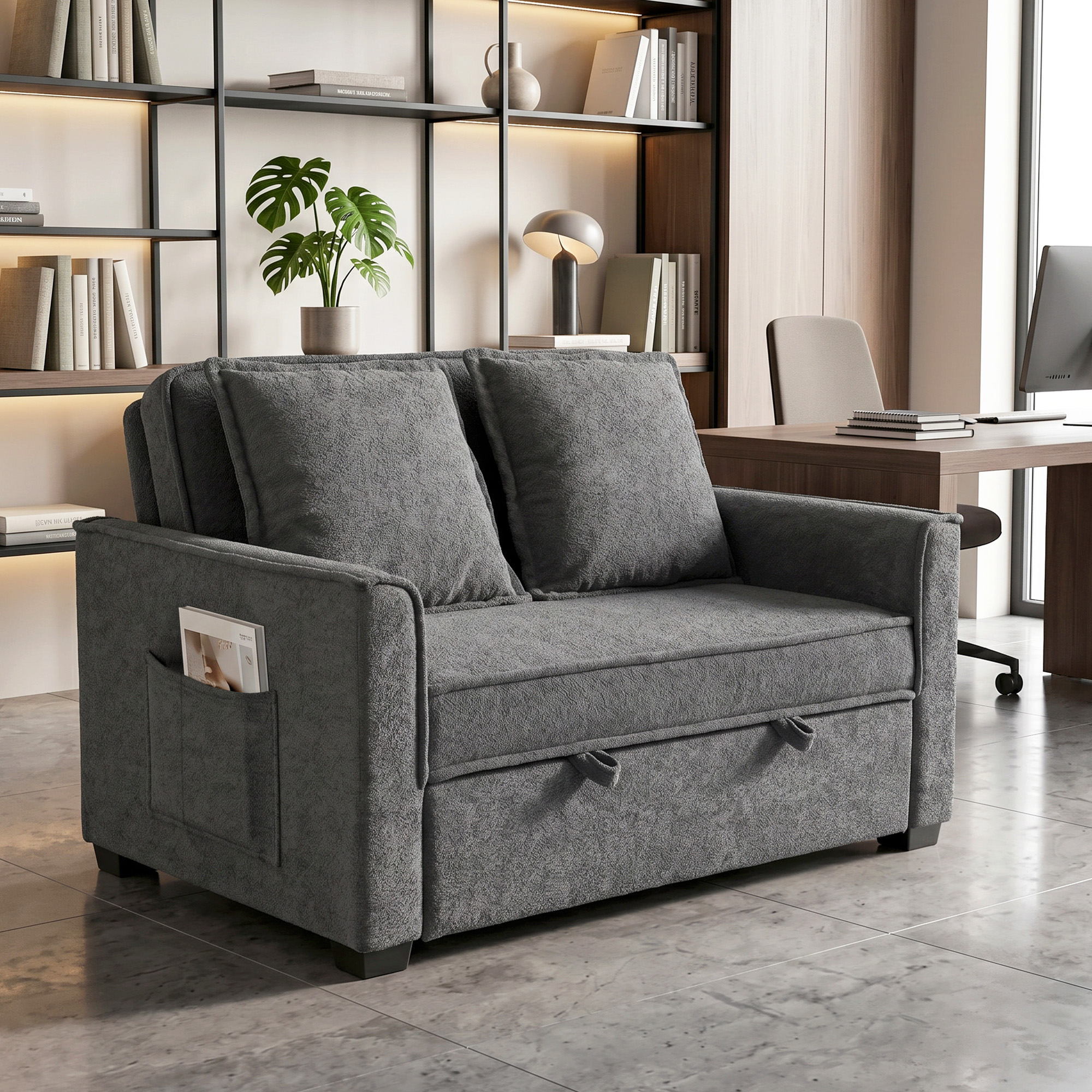 Sofá cama gris con dos cojines, bolsillos laterales y cajones extraíbles.