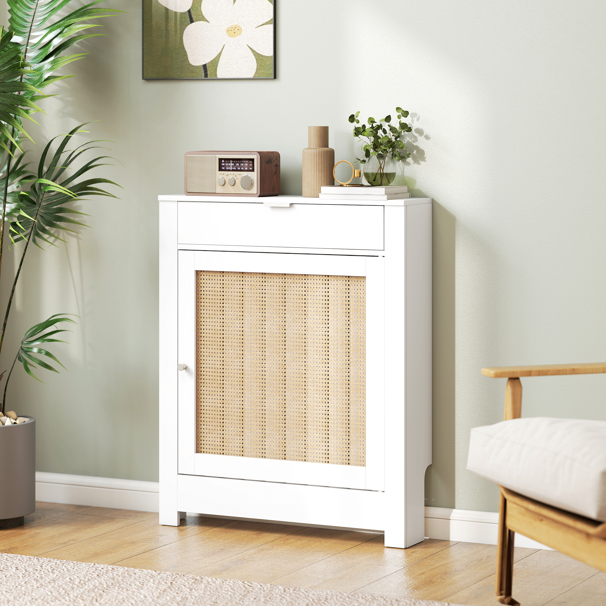 Un mueble blanco con inserción de ratán, al lado una radio, jarrón y libros.