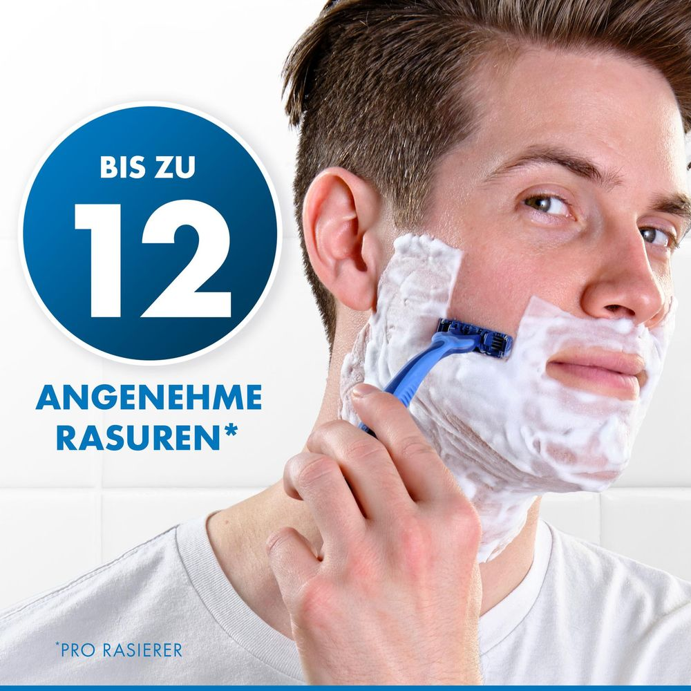 Uomo che si rade con schiuma e rasoio blu. Fino a 12 rasature confortevoli.