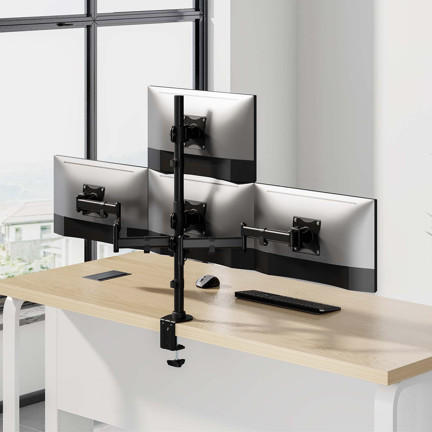 Un braccio triplo per monitor si aggancia a una scrivania in legno con mouse e tastiera.