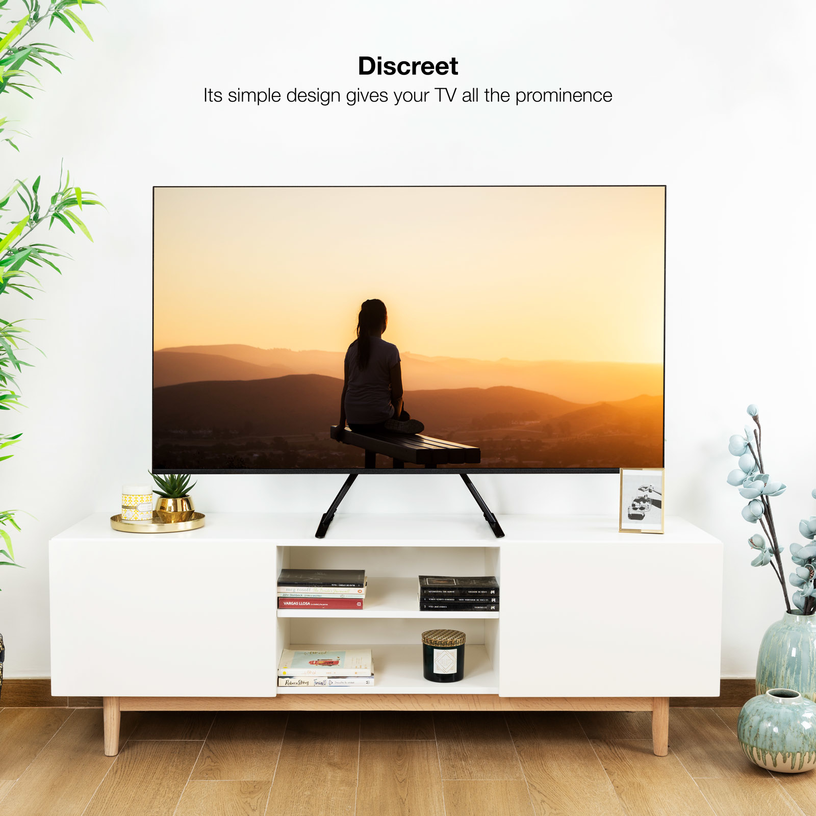 Un televisor sobre un mueble blanco con vista a montañas al atardecer. Diseño discreto.