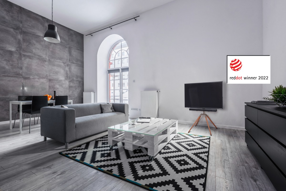 Modernes Wohnzimmer mit grauem Sofa, Holztisch, Teppich und Fernseher.