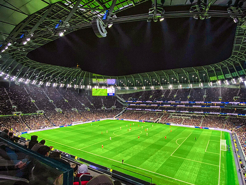 Partido de fútbol por la noche en un gran estadio lleno de espectadores.