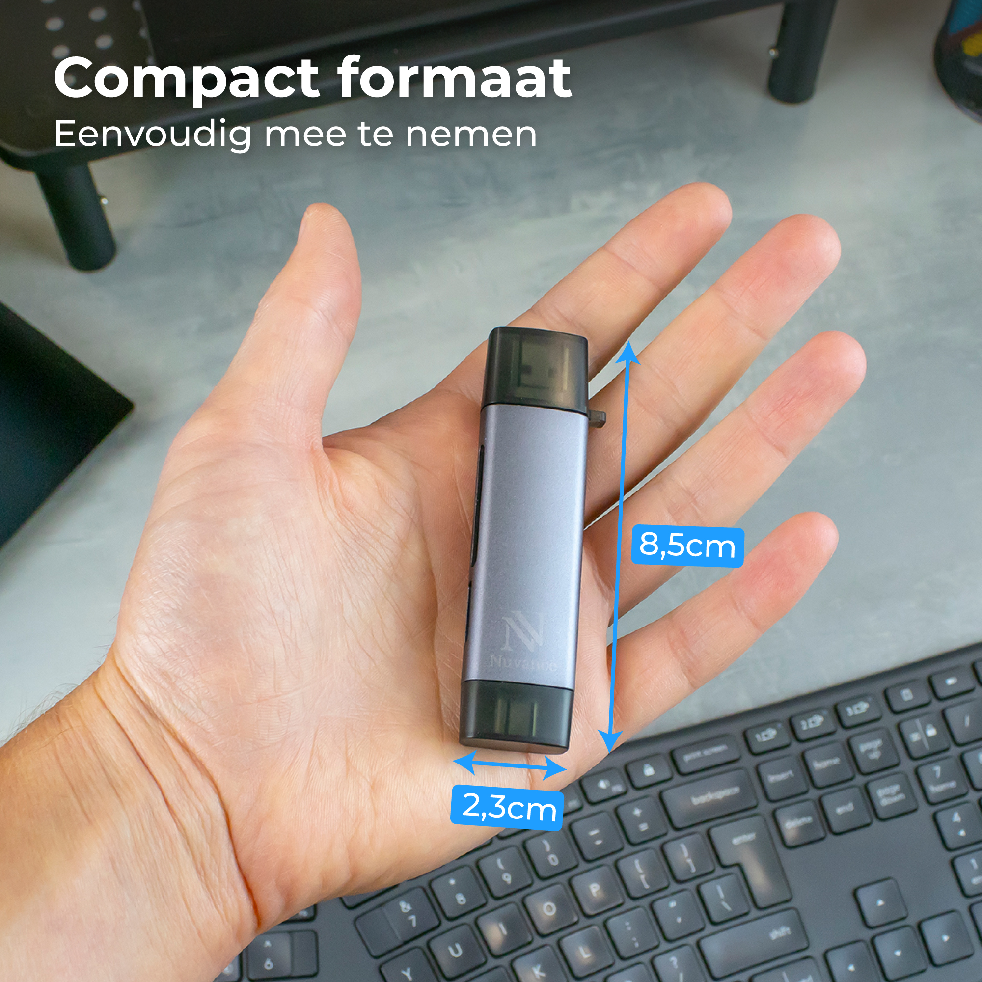 Een man houdt een compact grijs USB-apparaat (8,5x2,3cm) boven een toetsenbord.