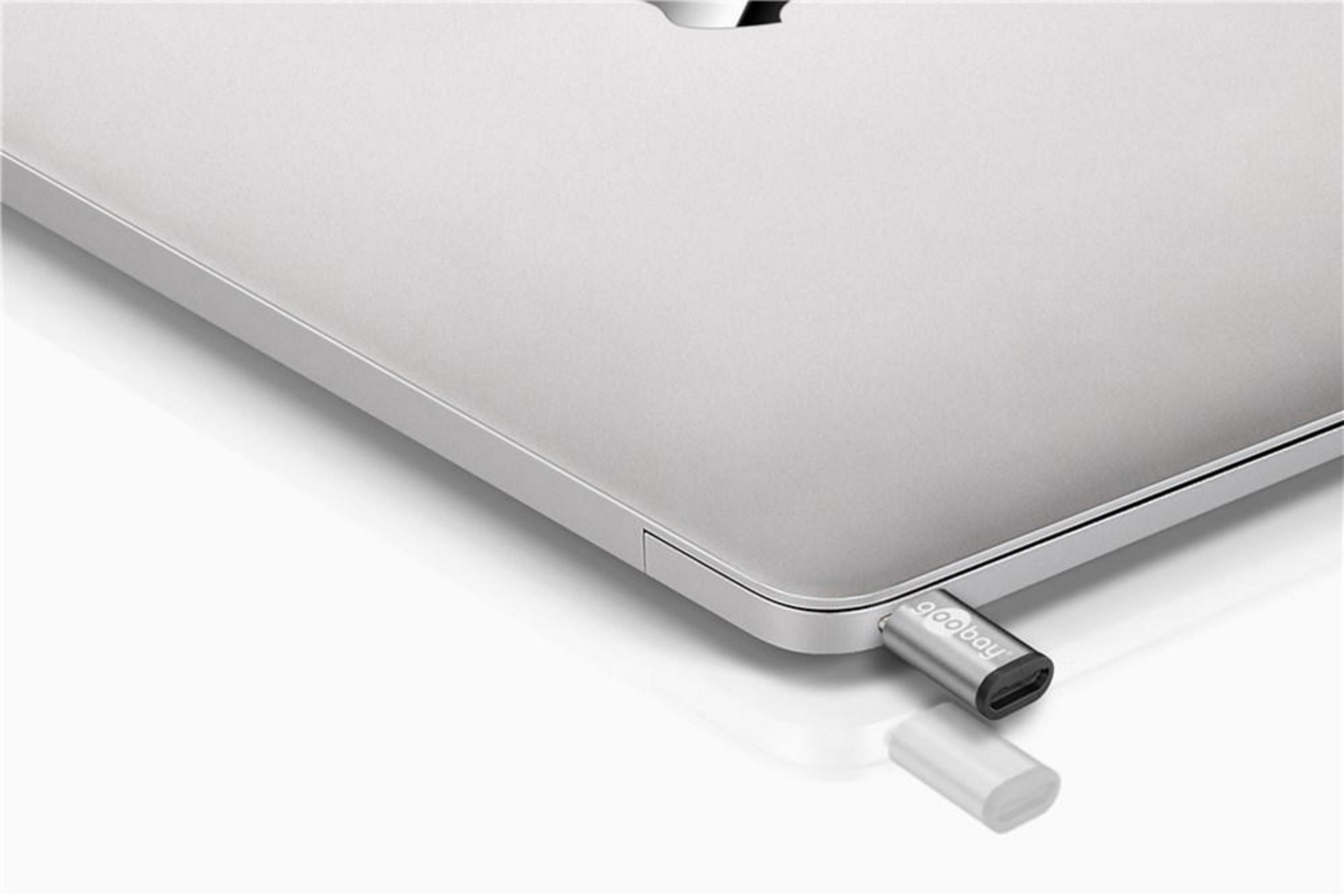 Ein silberner USB-C-Adapter wird in ein schlankes, silbernes Laptop-Gehäuse gesteckt.