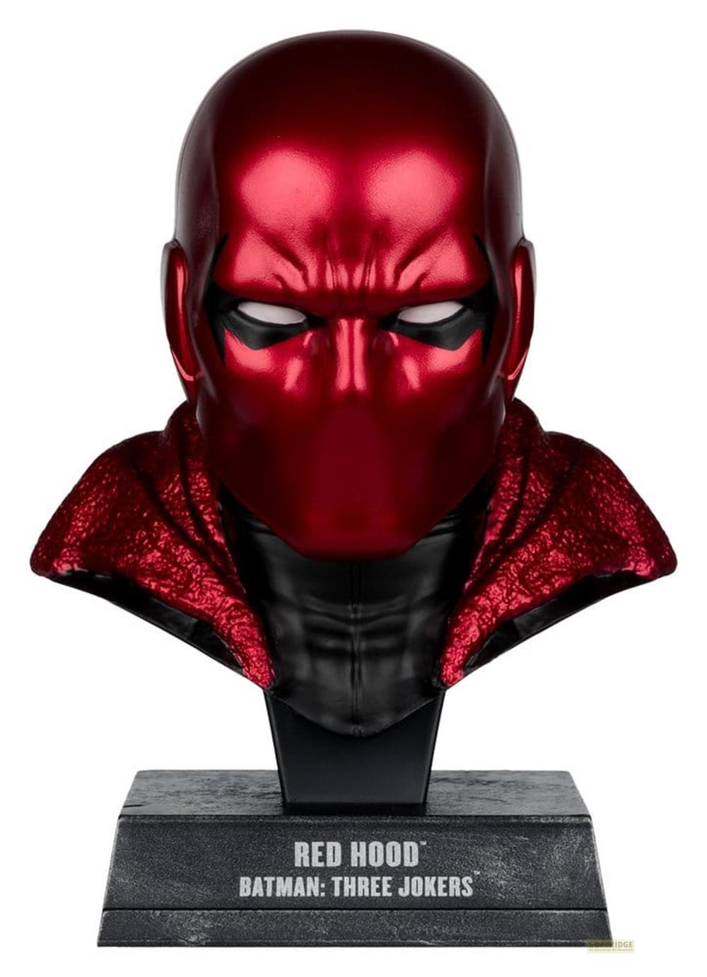 Rote Kapuze-Büste mit schwarzer Maske und Umhang auf einem Sockel.