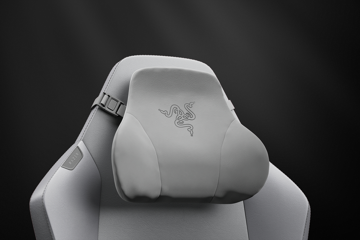 Silla gamer gris con almohada lumbar con logo de Razer. Fondo oscuro.