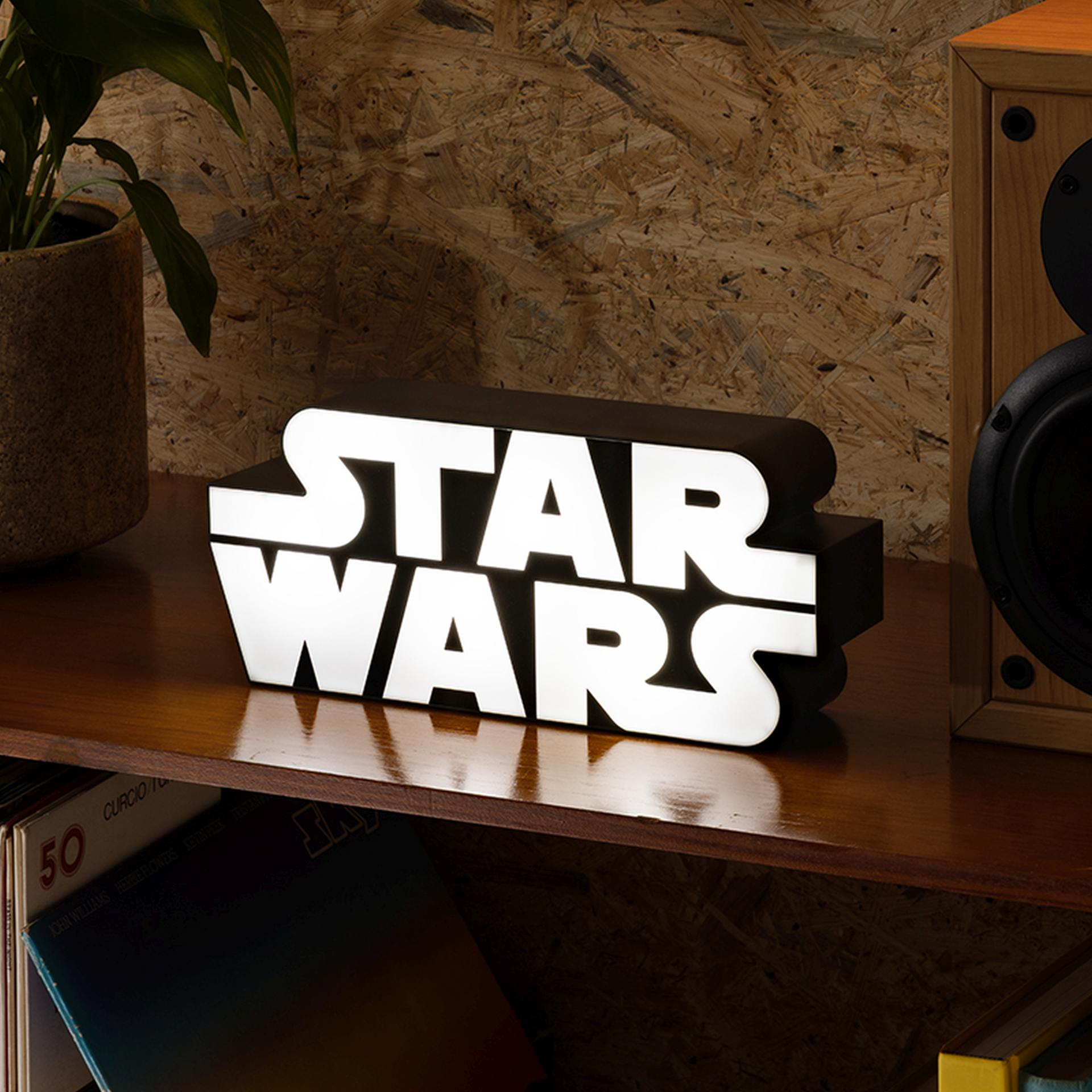 Ein leuchtendes Star Wars Logo auf einem Holzregal neben einem Lautsprecher.