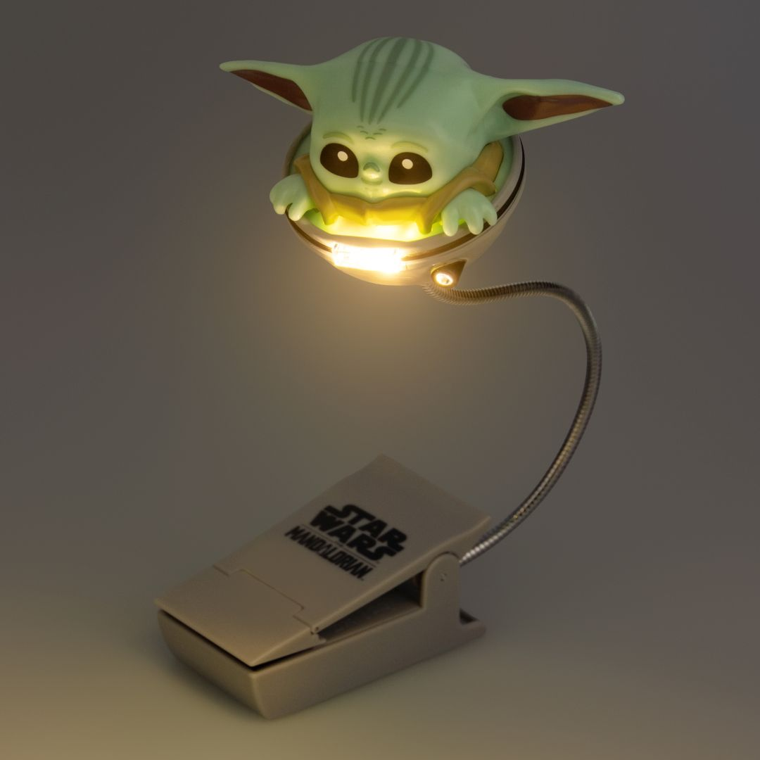 Lampka do czytania z klipsem Baby Yoda z logo Star Wars świeci.
