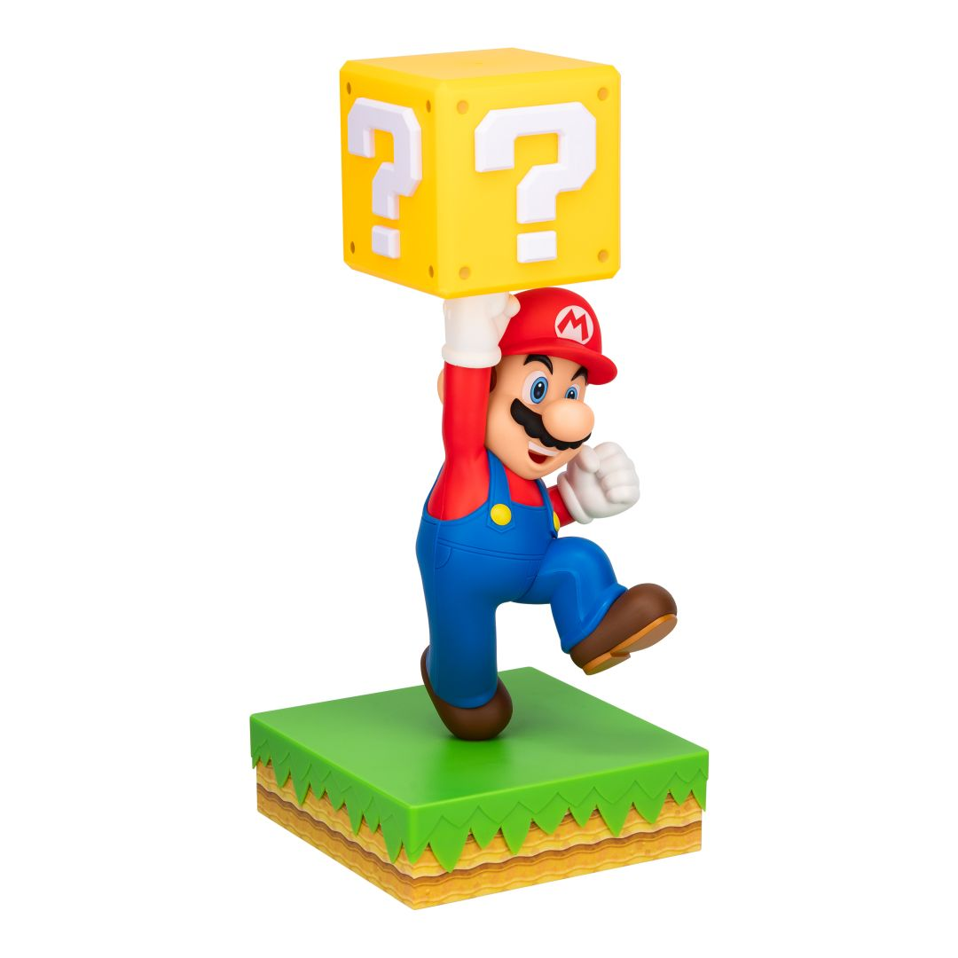 Figurka Mario trzyma żółty blok z pytajnikiem nad głową na zielonej platformie.