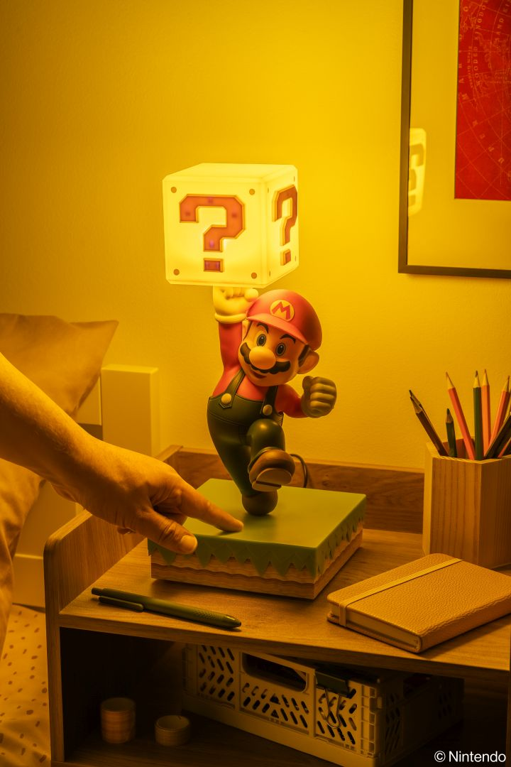Lampa Mario trzyma blok z pytajnikiem nad zieloną podstawą na stoliku nocnym.