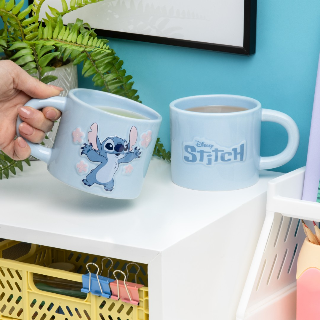 Zwei hellblaue Tassen mit Stitch-Motiv auf einem weißen Regal.