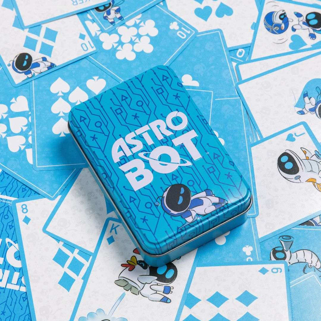 Une boîte en fer blanc bleue "ASTRO BOT" repose sur des cartes à jouer.