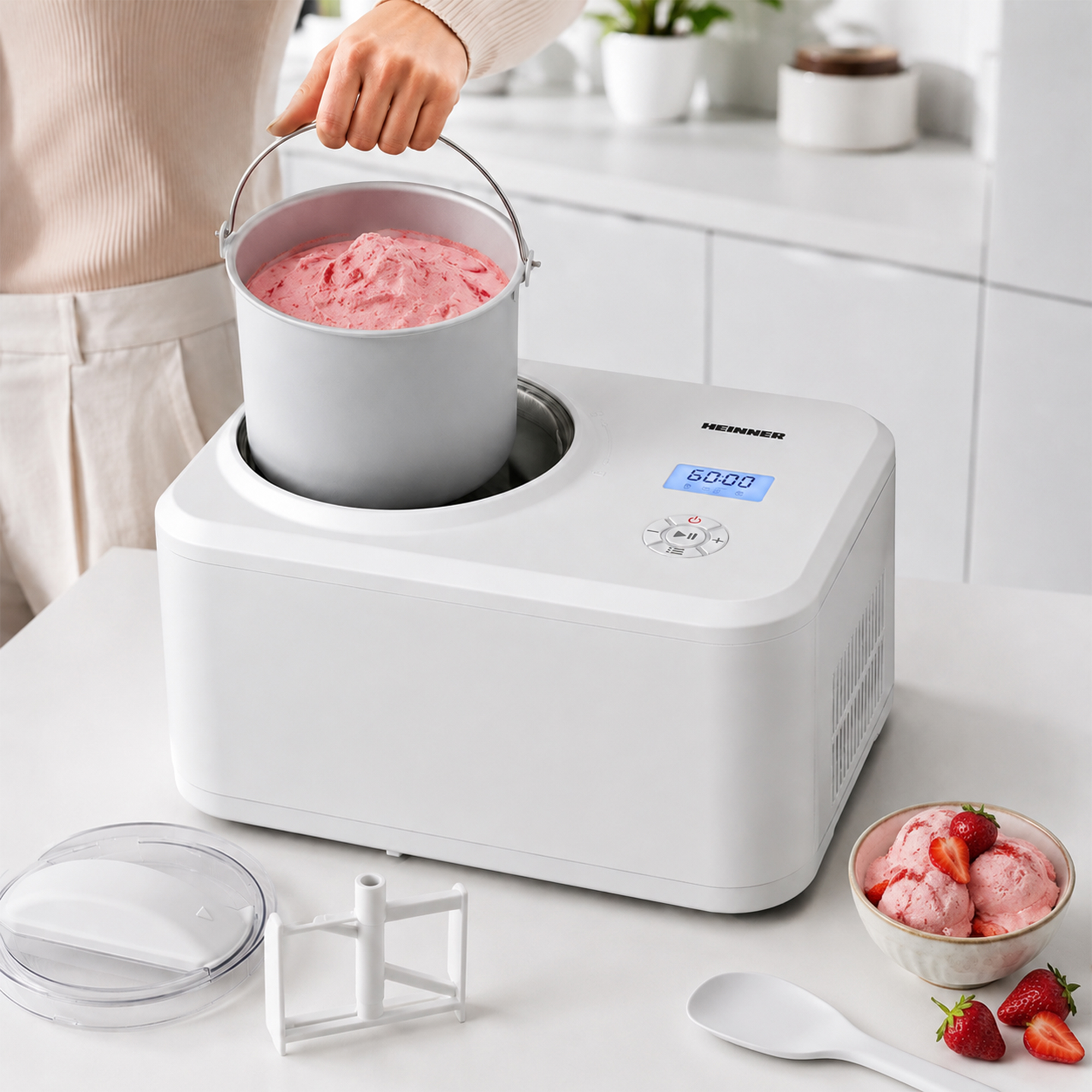 Eine Person benutzt eine Eismaschine, daneben eine Schüssel mit Erdbeereis.