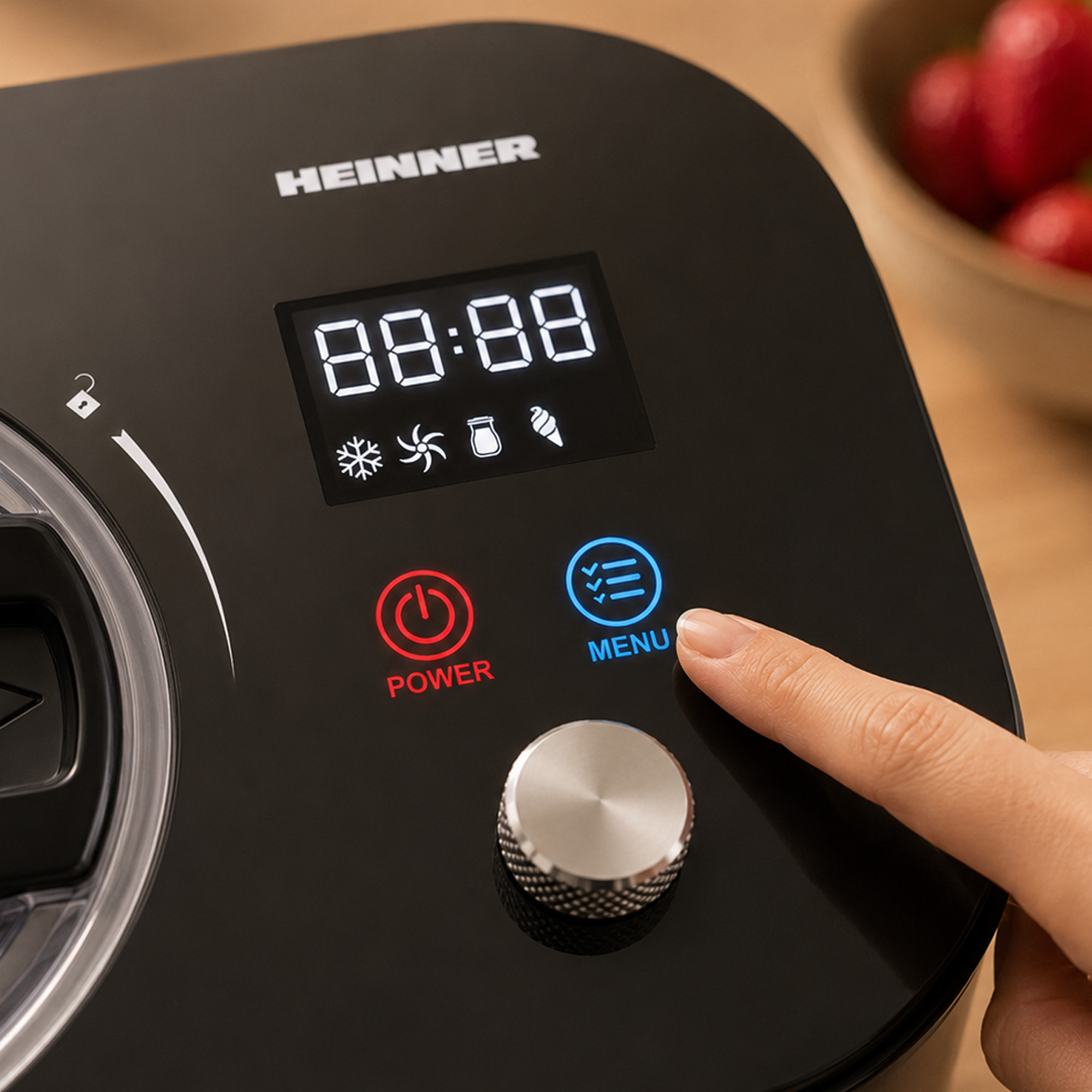 Eine Hand drückt die Menü-Taste auf einem schwarzen Gerät mit Display.