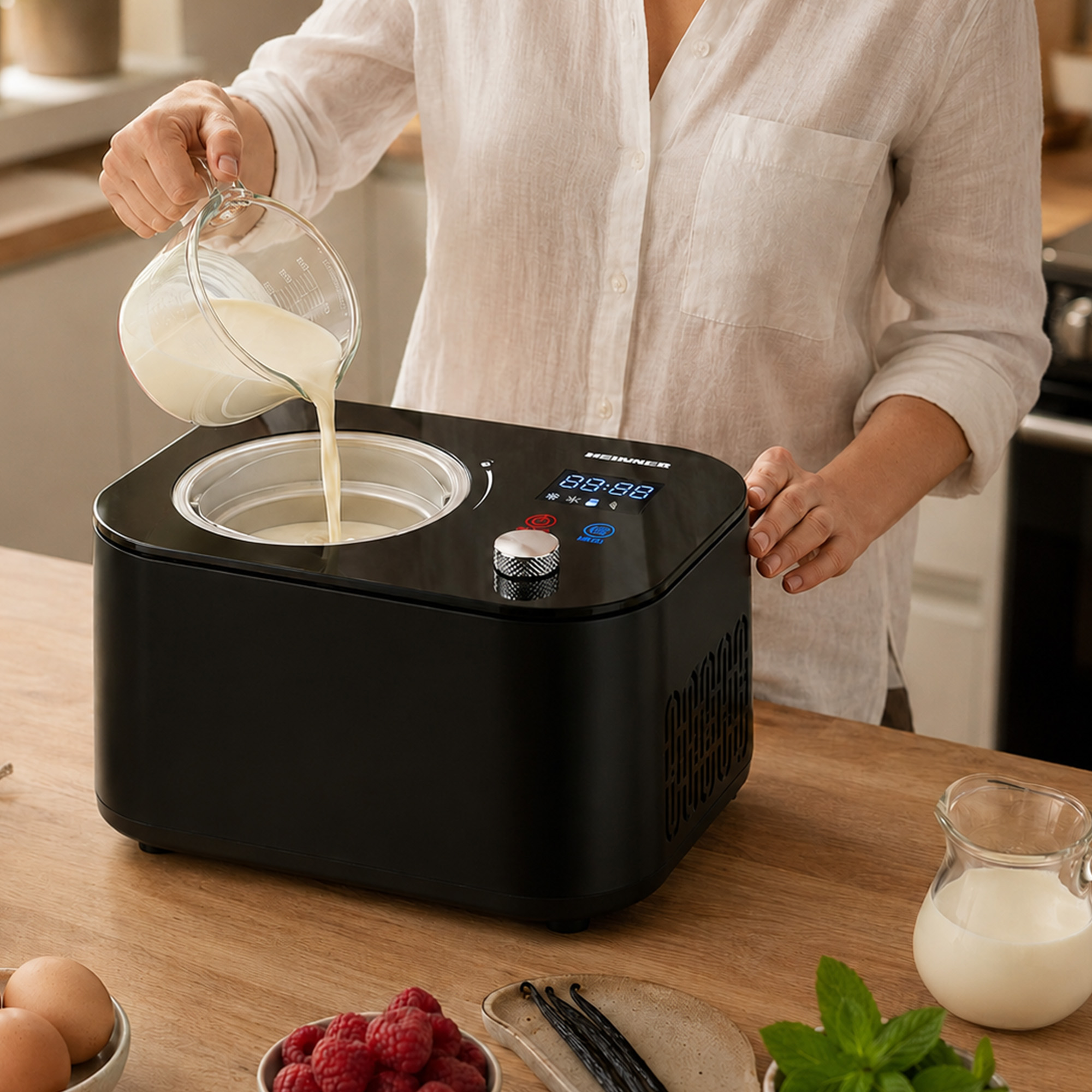 Flüssigkeit wird in eine Eismaschine gegossen, daneben Beeren, Eier und Vanille.