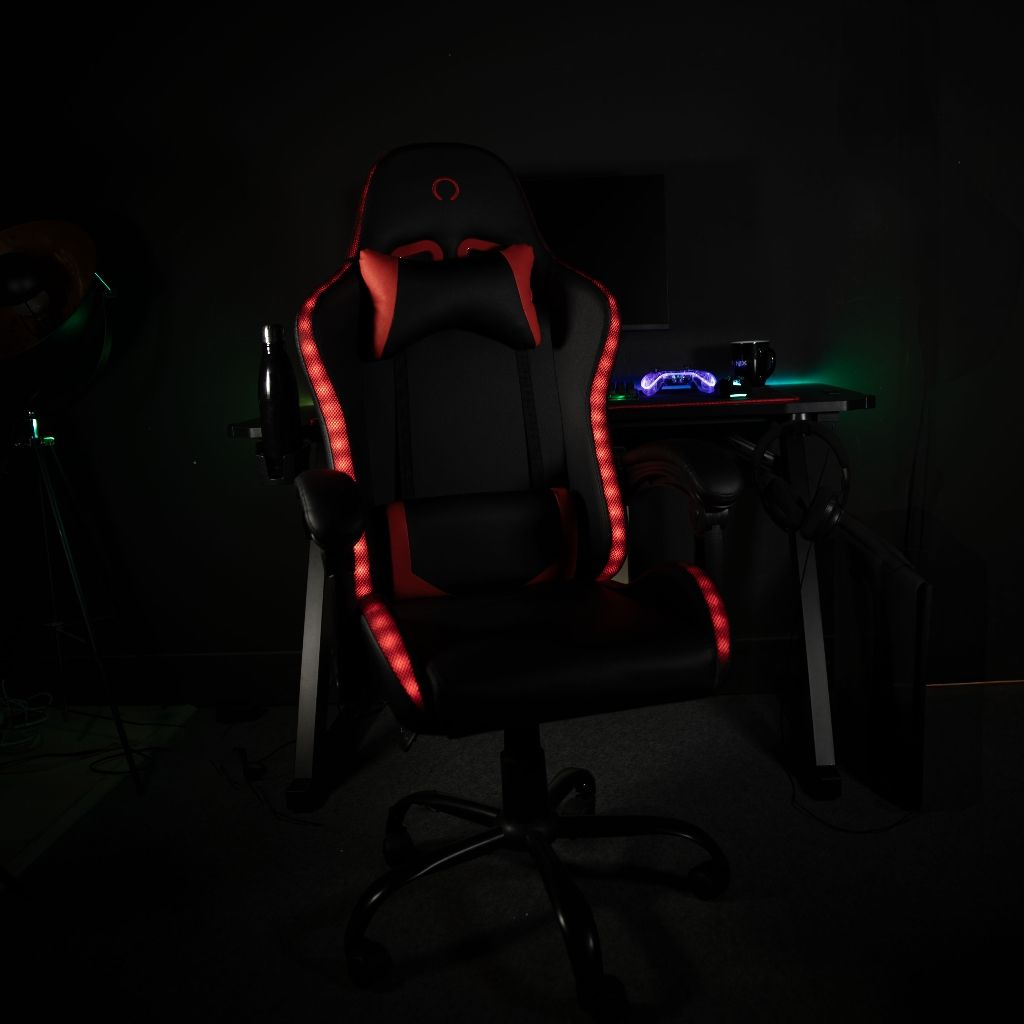Ein schwarzer Gaming-Stuhl mit roten LED-Akzenten steht vor einem Schreibtisch.