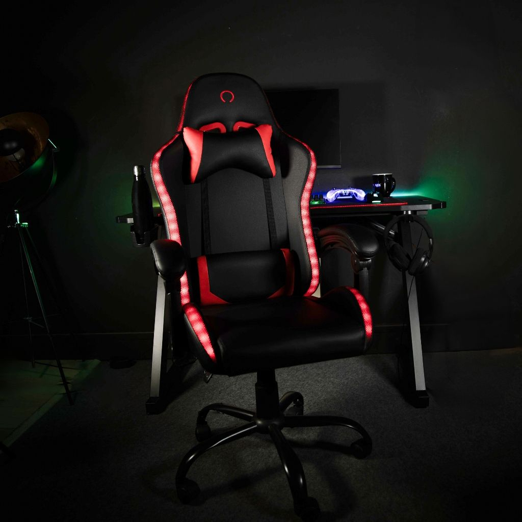 Ein schwarzer Gaming-Stuhl mit roten Akzenten und Beleuchtung steht vor einem Schreibtisch.