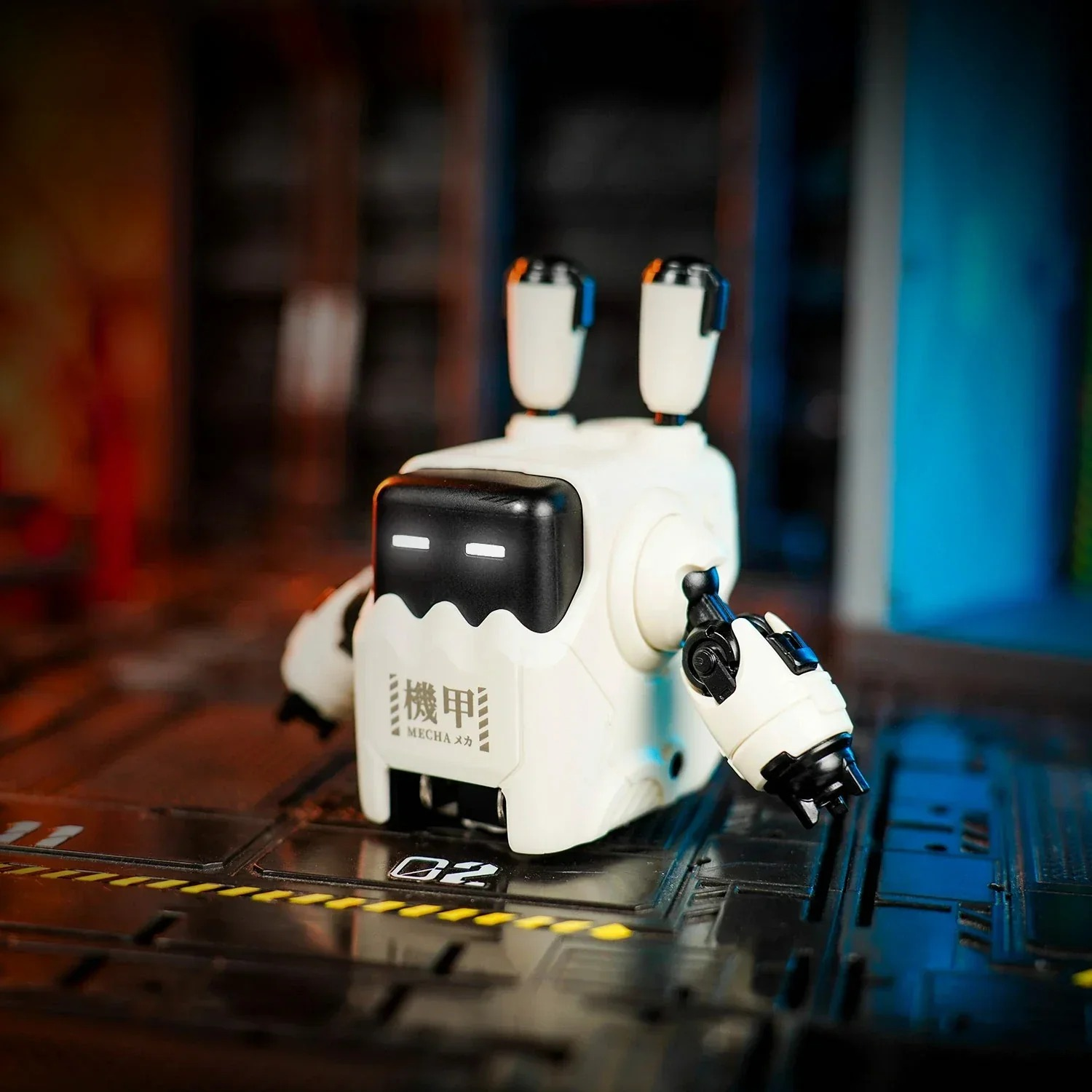 Siyah vurgulu küçük beyaz bir robot, sarı çizgili karanlık metalik bir yüzeyde duruyor.