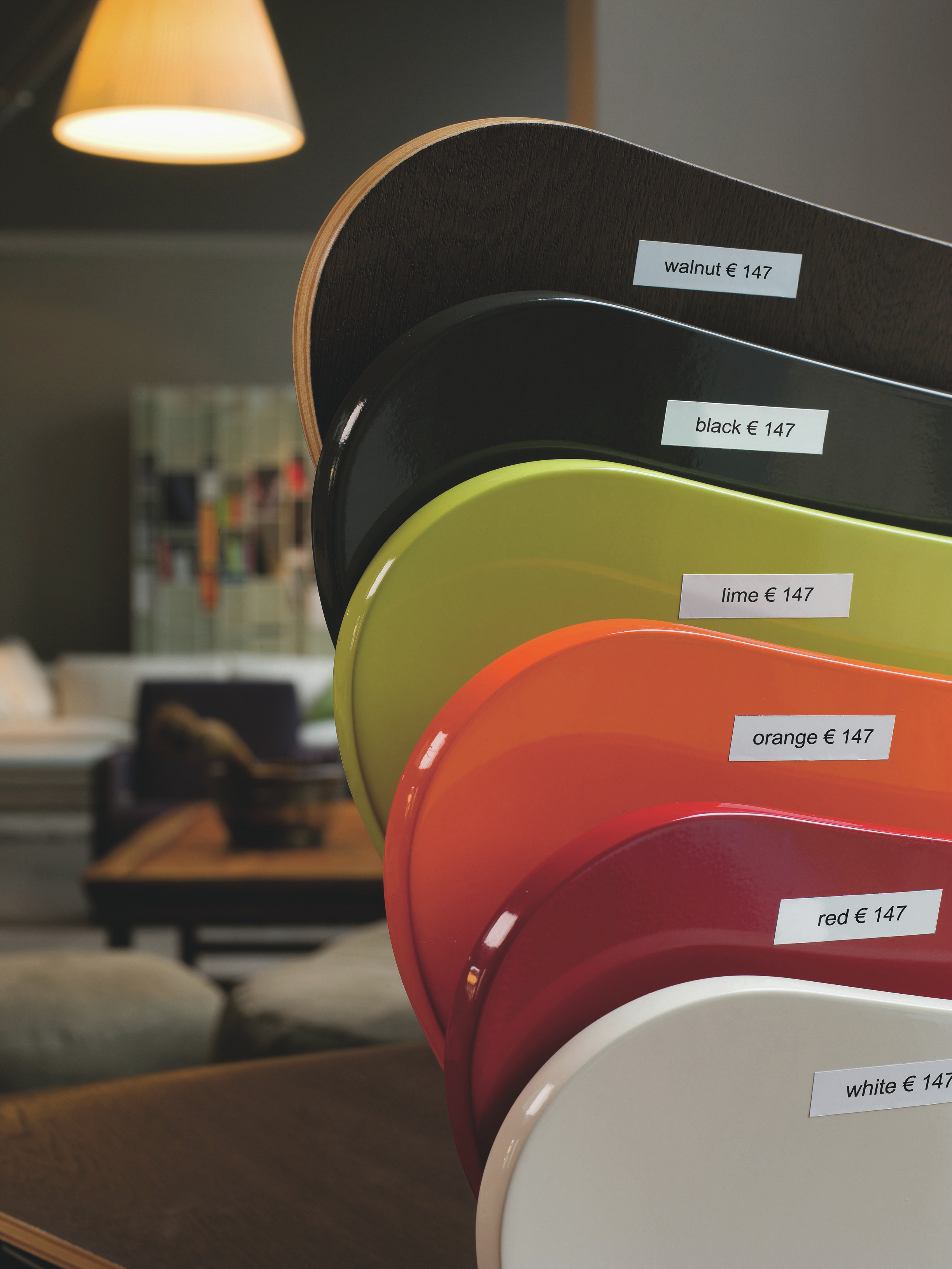 Diversi campioni di mobili colorati con cartellini dei prezzi, tra cui noce, nero, lime, arancione, rosso e bianco.