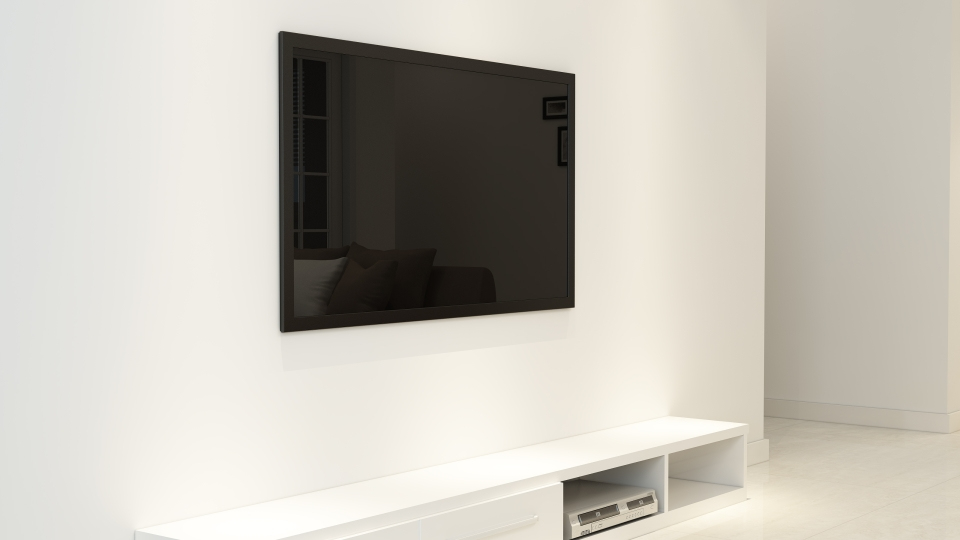 Una TV scura è appesa a una parete bianca sopra un mobile multimediale bianco.