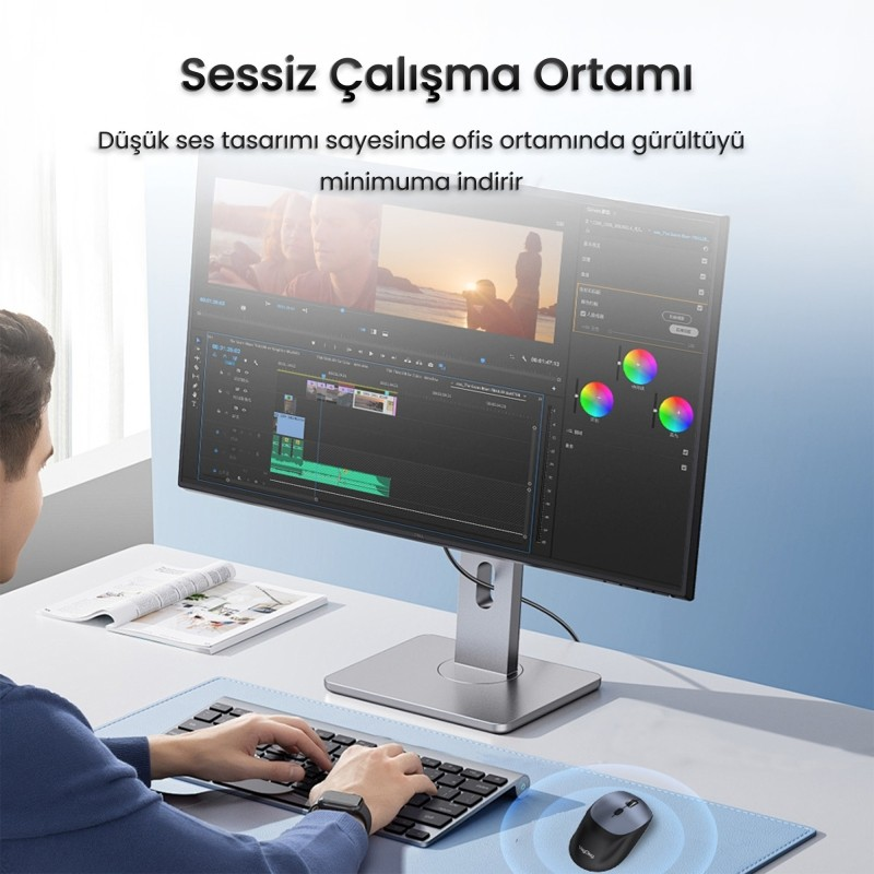 Adam video düzenleme yazılımı gösteren monitör önünde klavyede yazıyor.