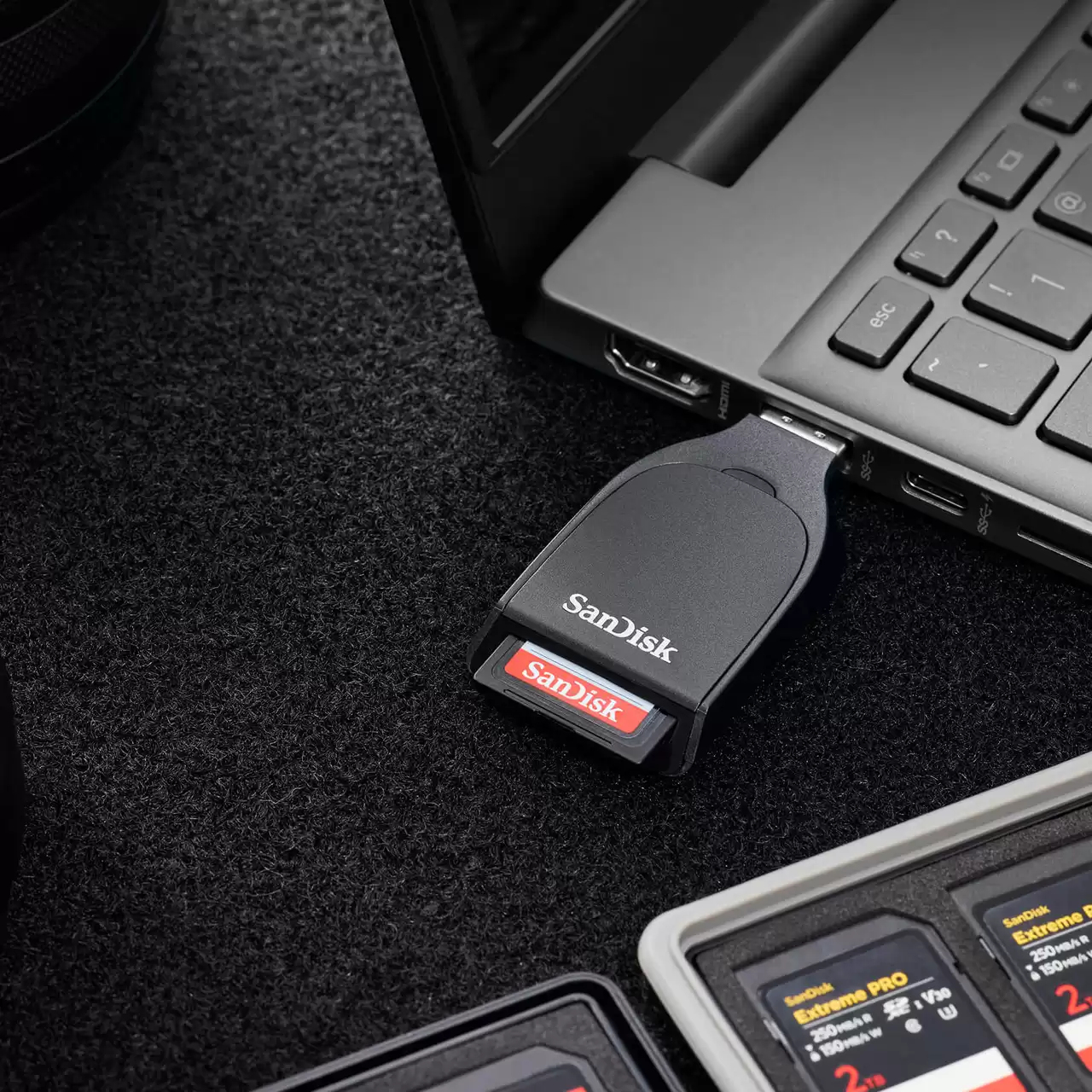 Ein SanDisk-Kartenleser ist in einen Laptop eingesteckt, daneben sind Speicherkarten.