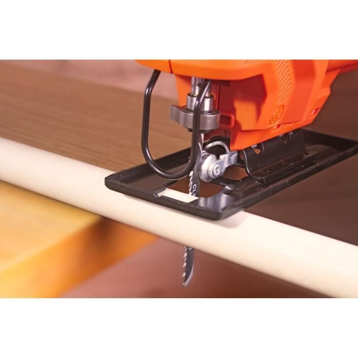 Un seghetto alternativo arancione taglia un tubo bianco su legno.