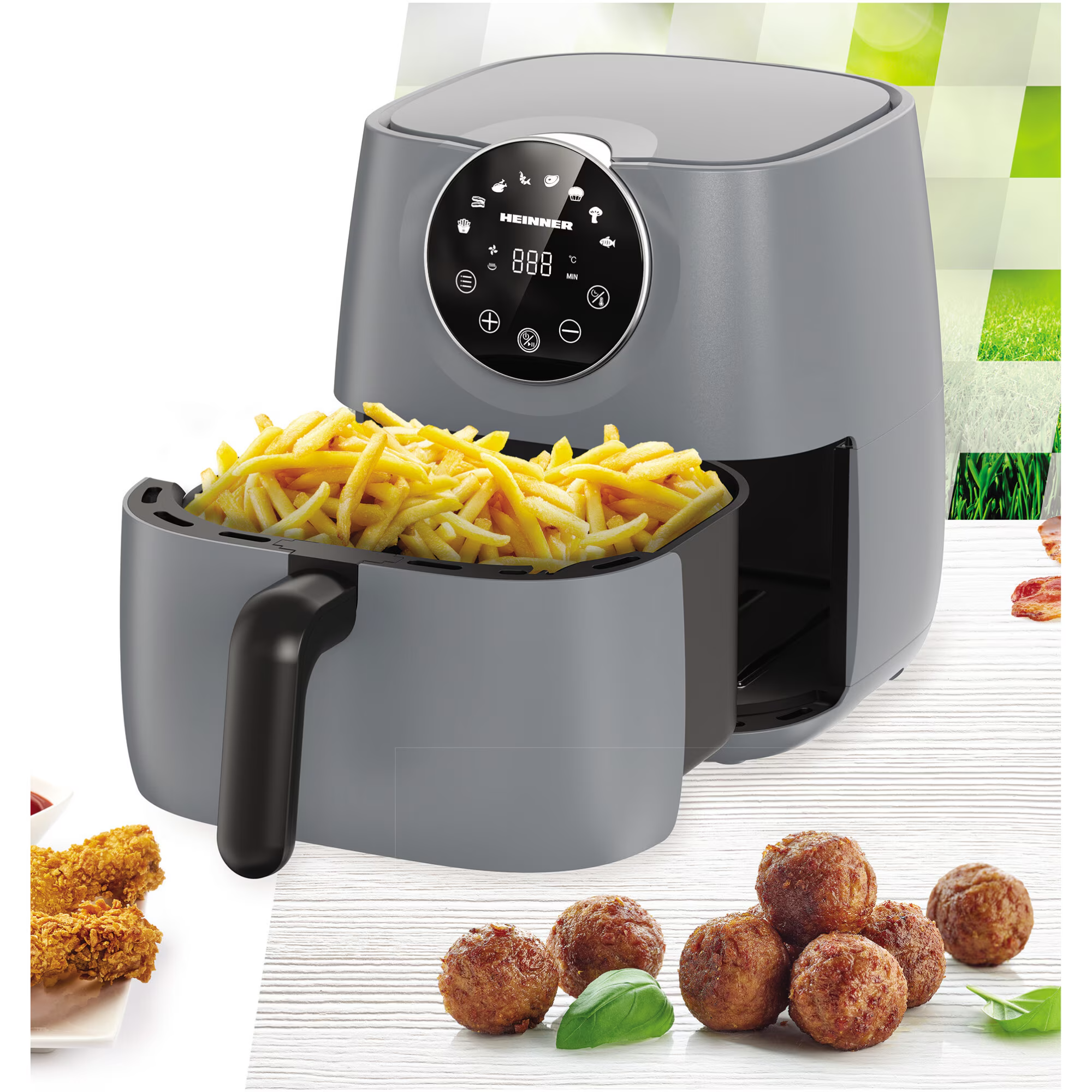 Grijze airfryer met frietjes, gehaktballetjes en kipstukjes.
