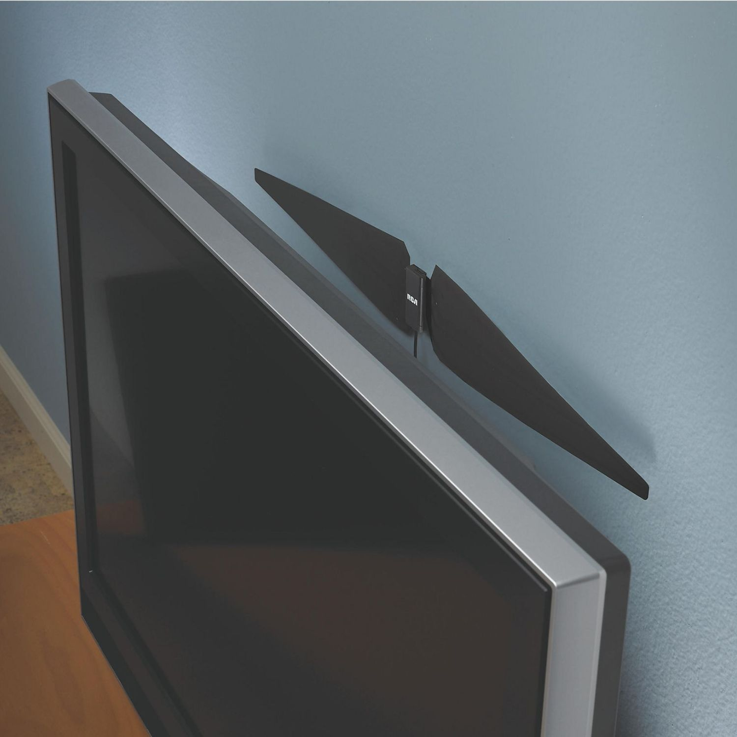 Ein Flachbildfernseher mit silbernem Rahmen ist an einer blauen Wand mit schwarzen RCA-Lautsprechern montiert.