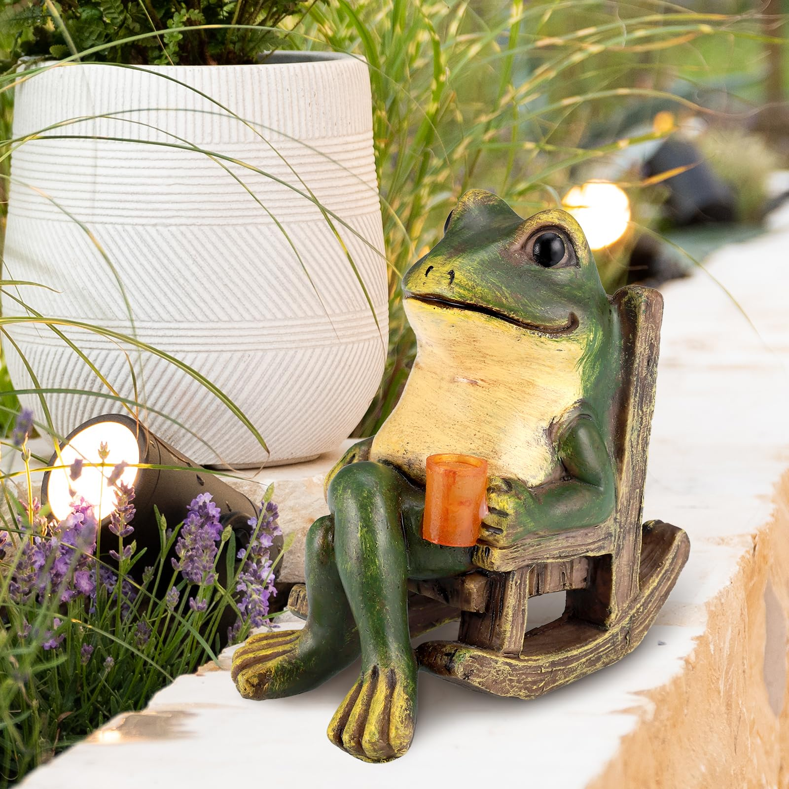 Eine Froschfigur sitzt in einem Schaukelstuhl und hält ein Getränk.
