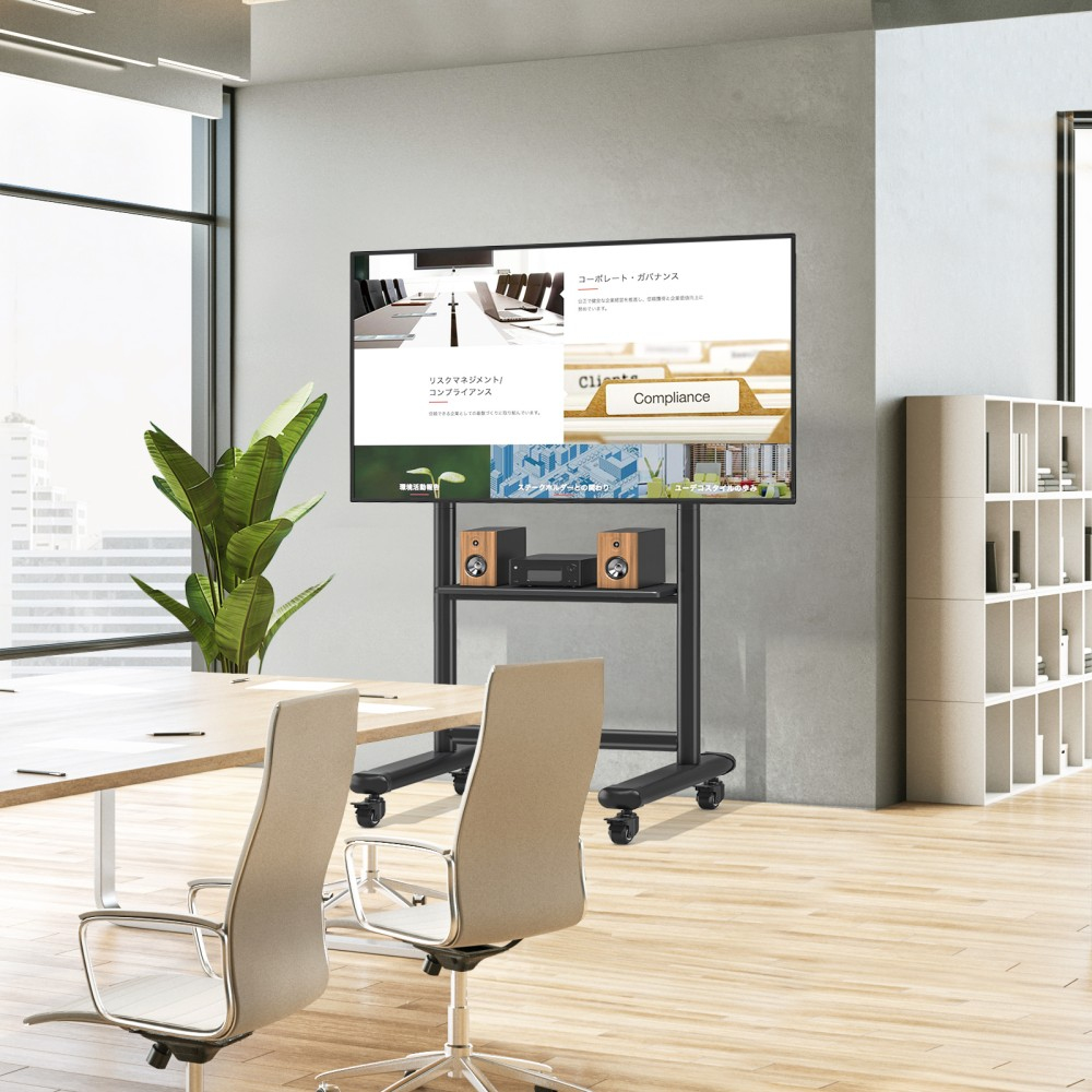 Modernes Büro mit einem Fernseher auf einem Ständer, Lautsprechern und Stühlen um einen Tisch.
