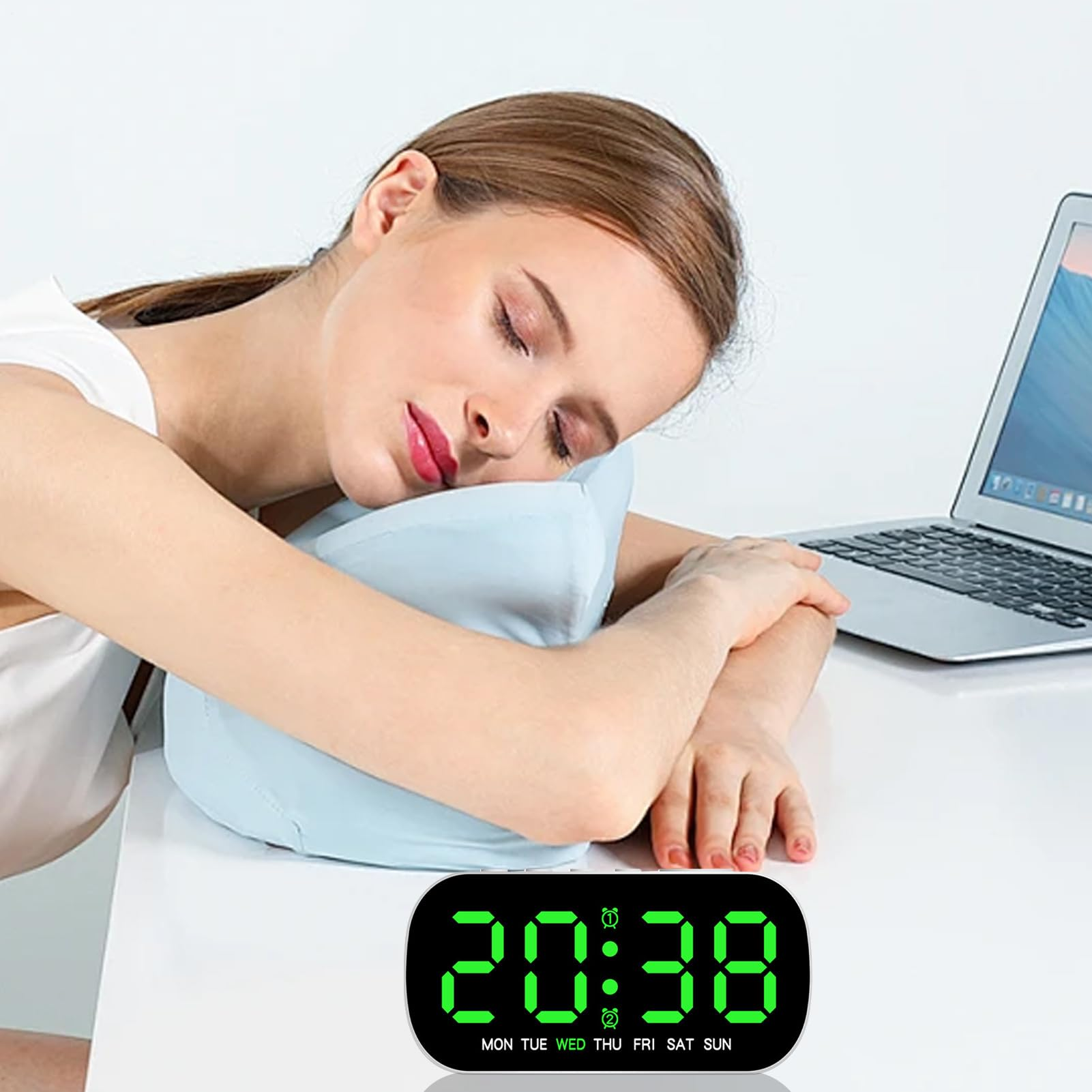 Eine Frau schläft auf einem blauen Kissen, ein Laptop und ein digitaler Wecker sind auf dem Tisch.