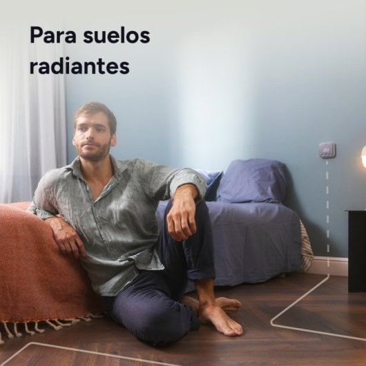Man zit op de vloer voor een bed, thermostaat aan de muur.