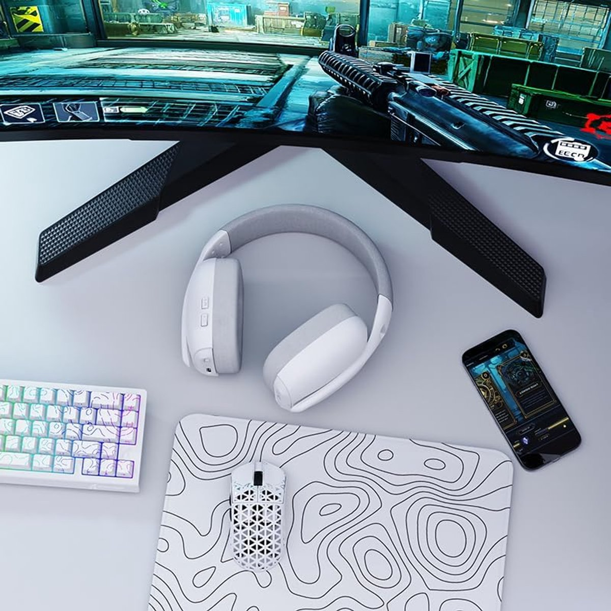 A desk setup with gaming gear: monitor, headphones, keyboard, mouse, mousepad, and phone.