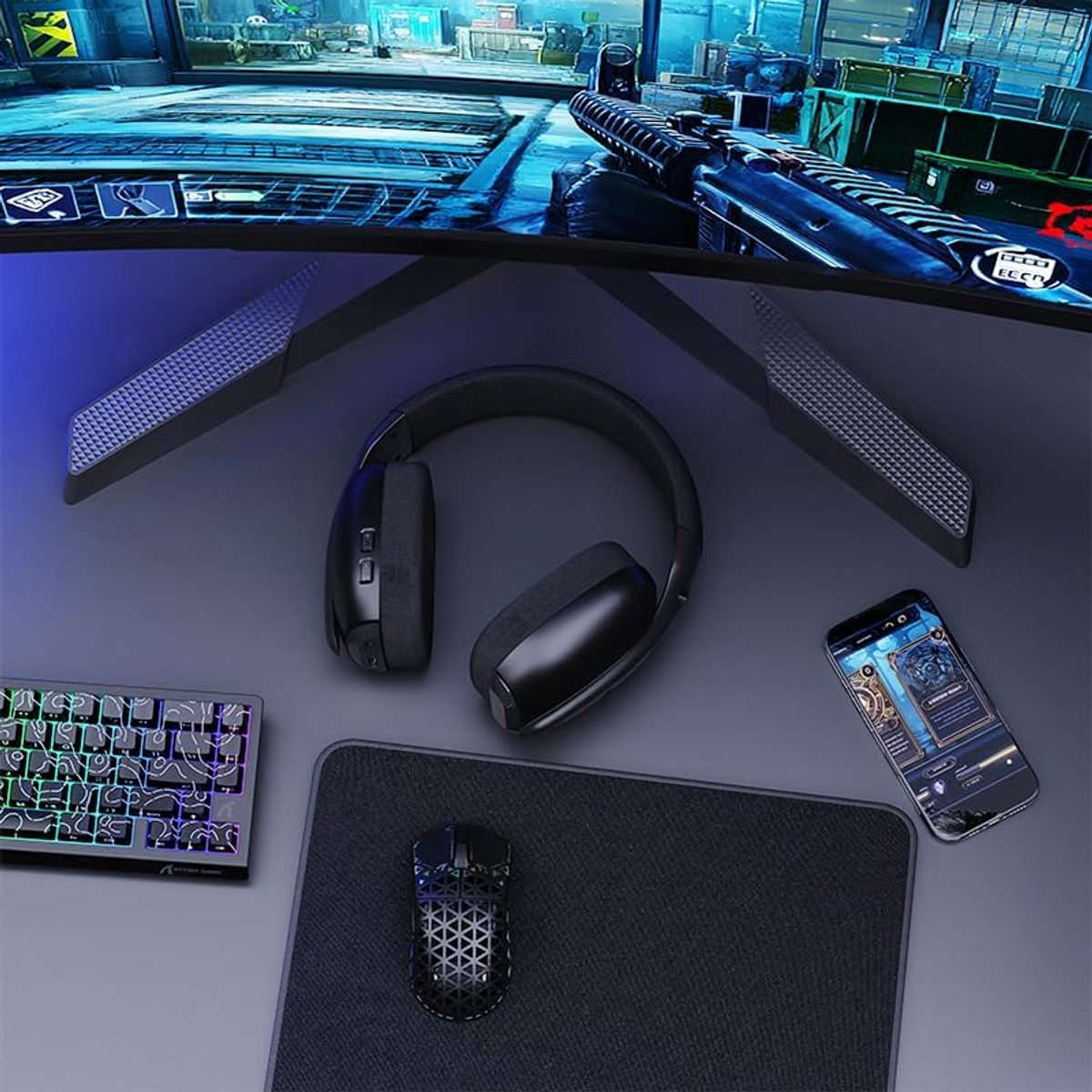 A gaming setup featuring a monitor, keyboard, mouse, headset, and phone.