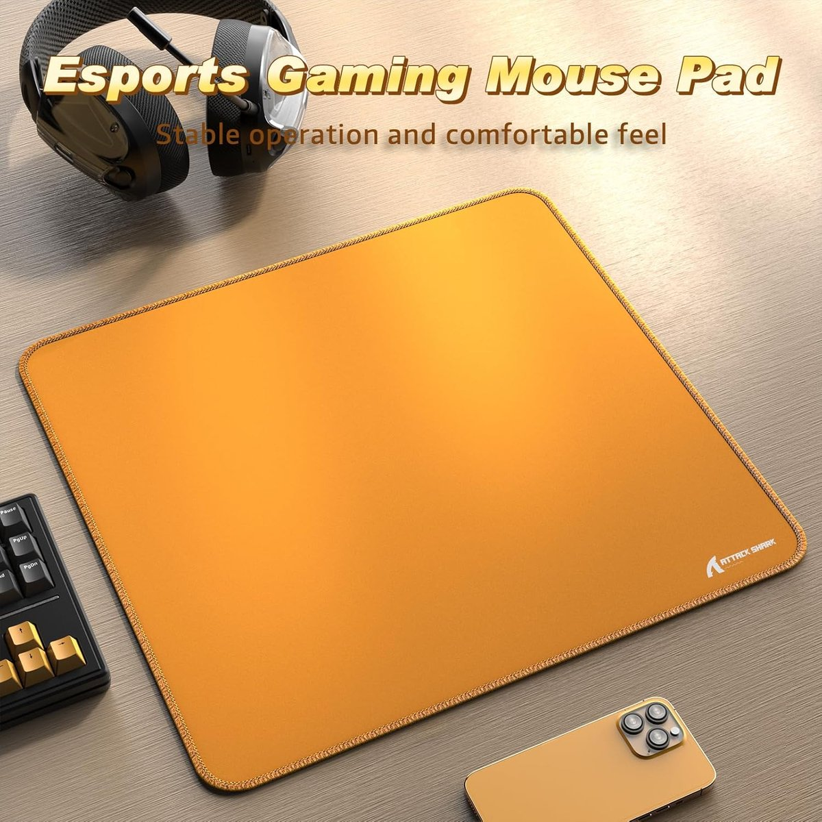 An orange gaming mouse pad with headphones, keyboard, and phone.