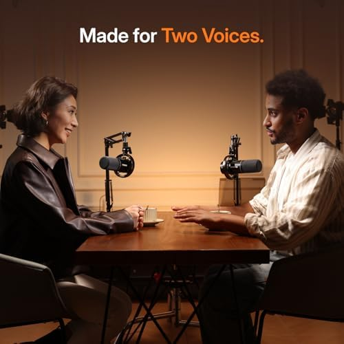 Man and woman sit at a table with microphones, ready for recording.