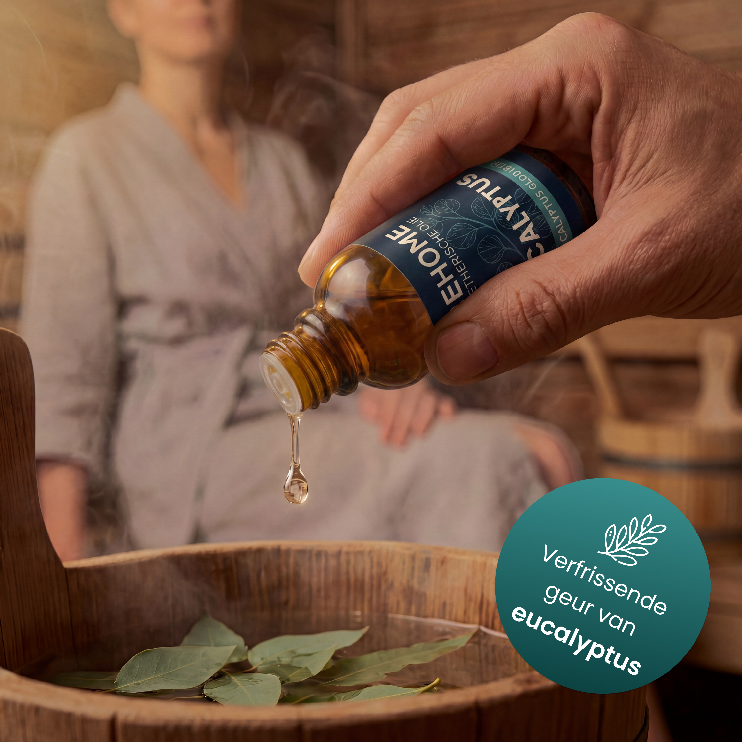 A drop of essential oil falls into a wooden tub with water and eucalyptus leaves.