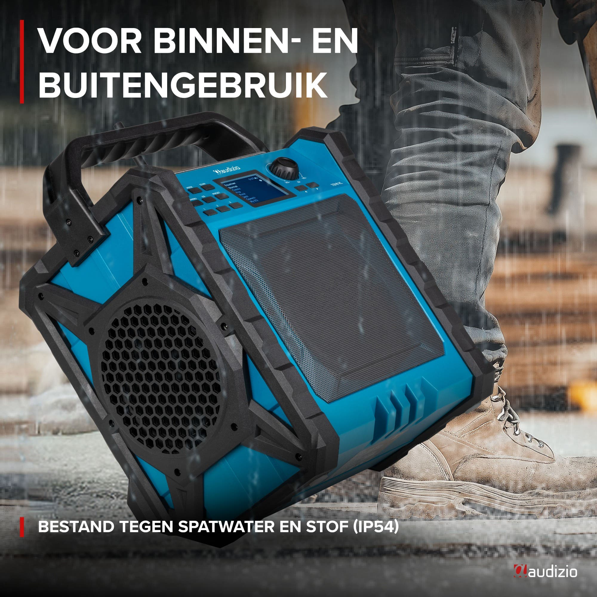 Ein blauer tragbarer Lautsprecher mit schwarzem Gitter und Griff, steht auf nassem Boden.