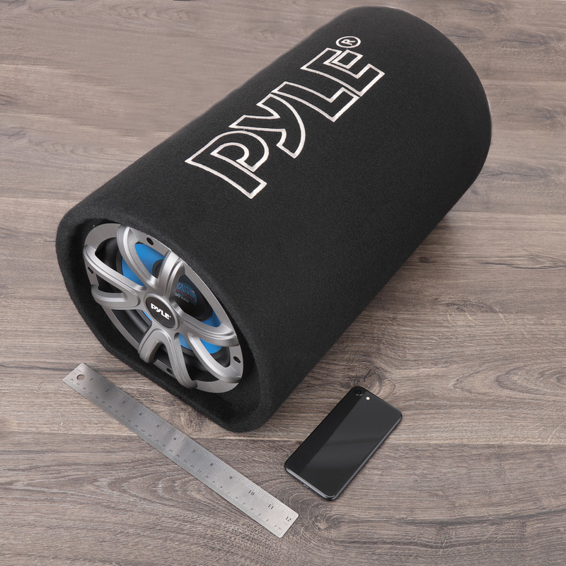 Schwarzer zylindrischer Pyle-Subwoofer mit silbernem Lautsprechergrill auf Holzboden, mit Lineal und Handy.