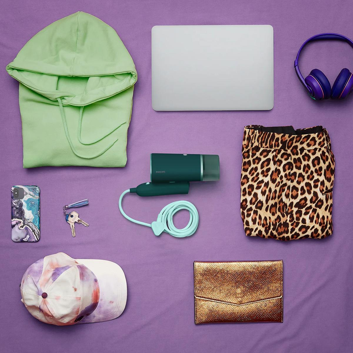 Grüner Hoodie, Laptop, Kopfhörer, Dampfbügeleisen, Hose mit Leopardenmuster, Handy, Schlüssel, Kappe, goldene Brieftasche.