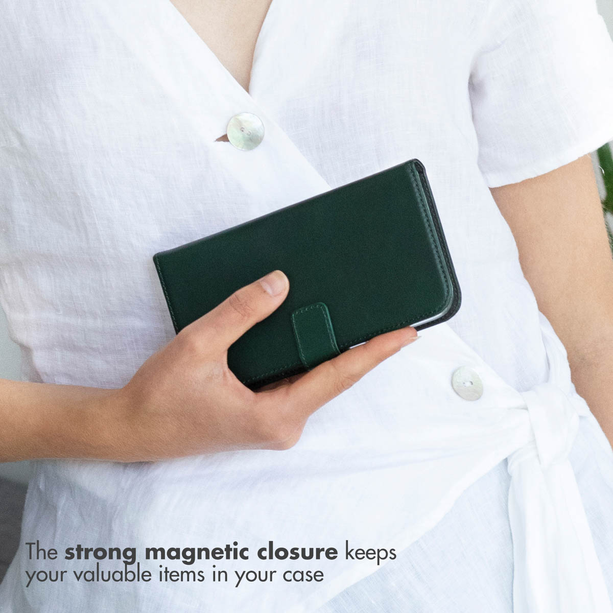 Une main tient un étui de téléphone vert foncé, paysage, contre une chemise blanche.
