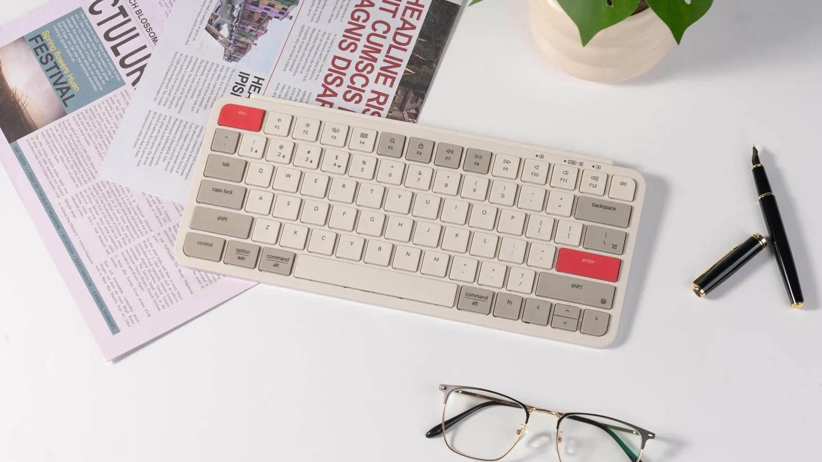 Klawiatura, gazeta, okulary i długopis na białym biurku.