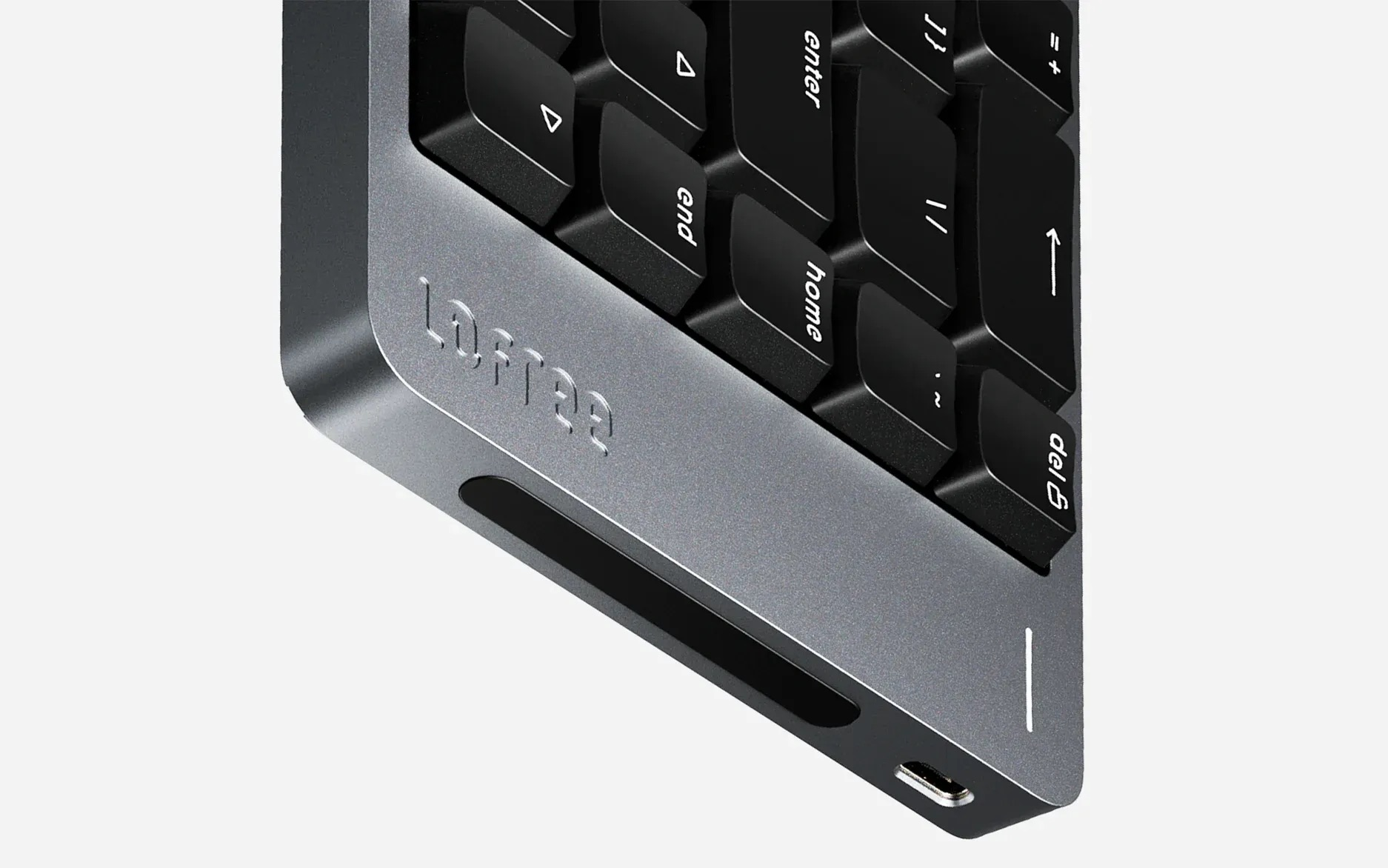 Zbliżenie szarej klawiatury, pokazujące czarne klawisze, logo marki i port USB-C.