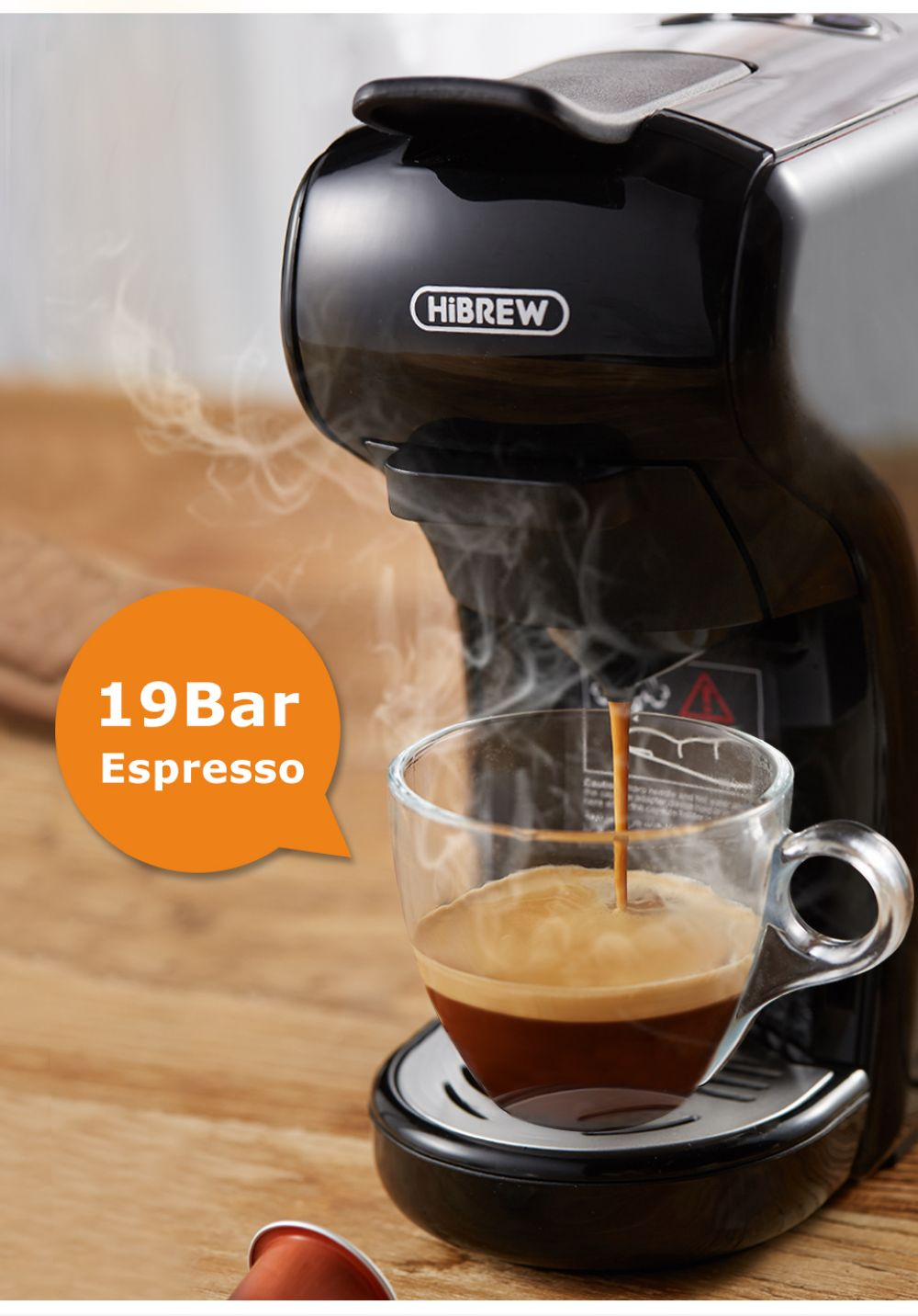 Una macchina per caffè espresso HiBREW nera prepara il caffè in una tazza di vetro trasparente. Il vapore sale.