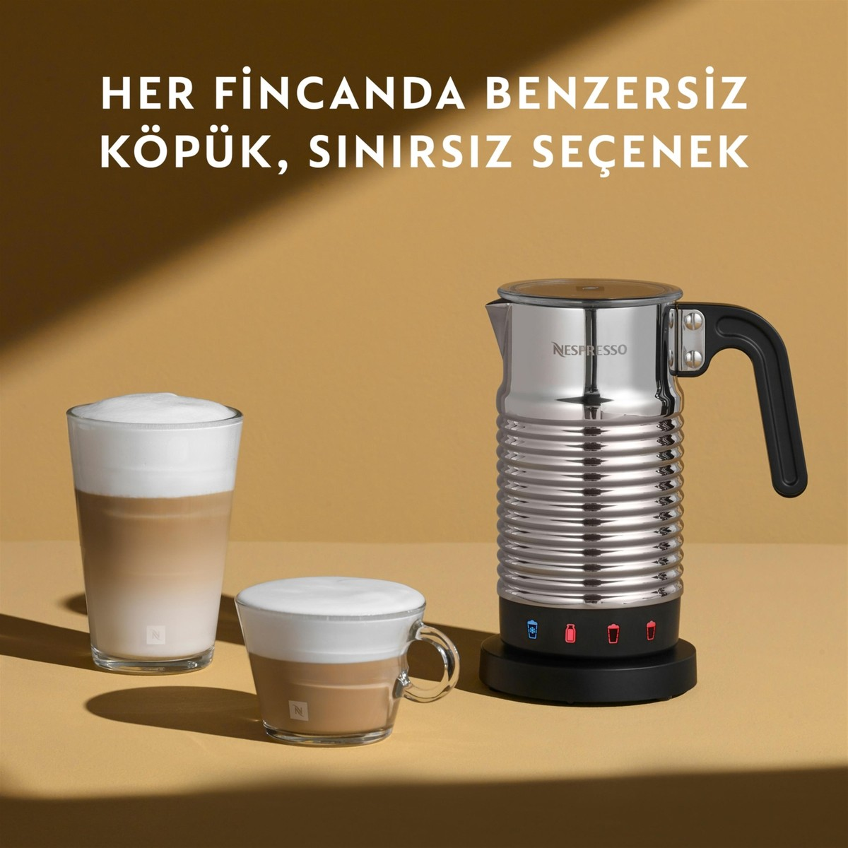 Nespresso süt köpürtücü, köpüklü süt kahveli iki bardak yanında.